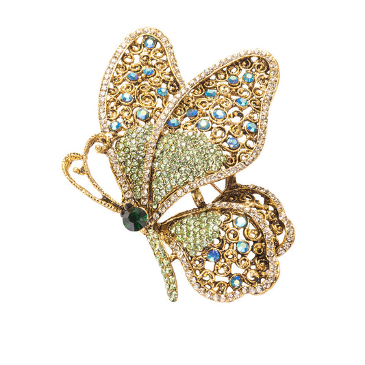 Butterfly-shaped brooch with gold frame and gemstones on a white background