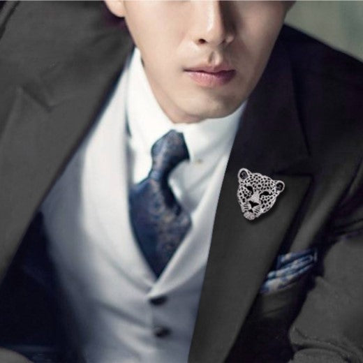Man wearing a suit with a leopard brooch and patterned tie.