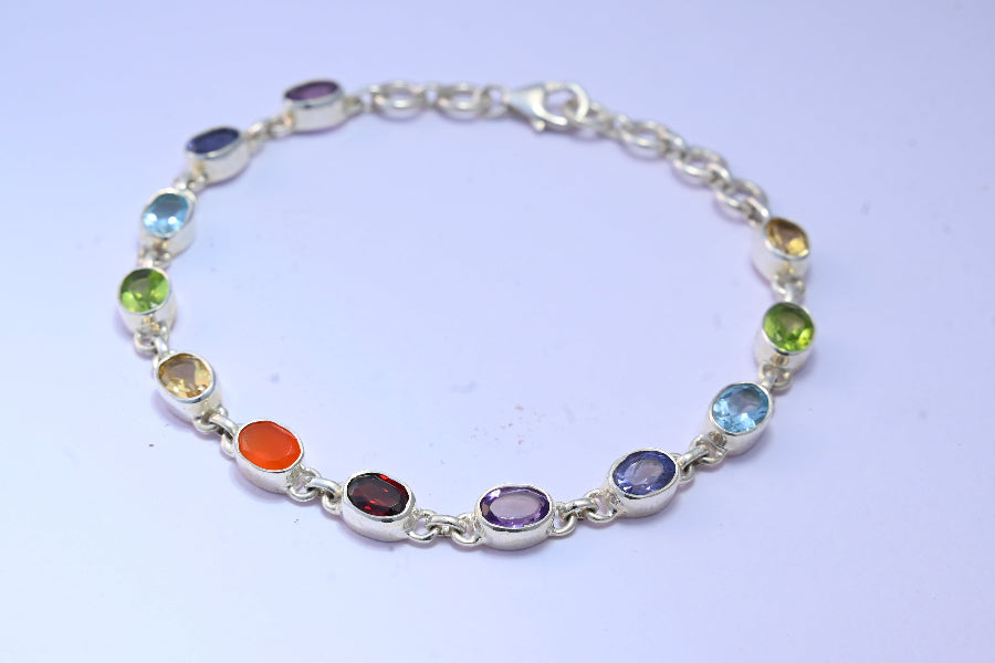 Silver bracelet with Chakra multicolored gemstones on a light purple background
