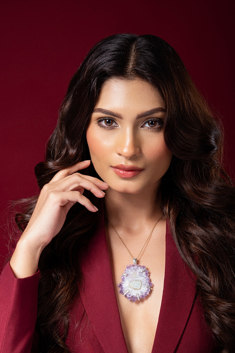 Woman wearing a deep neckline outfit with a necklace against a red background