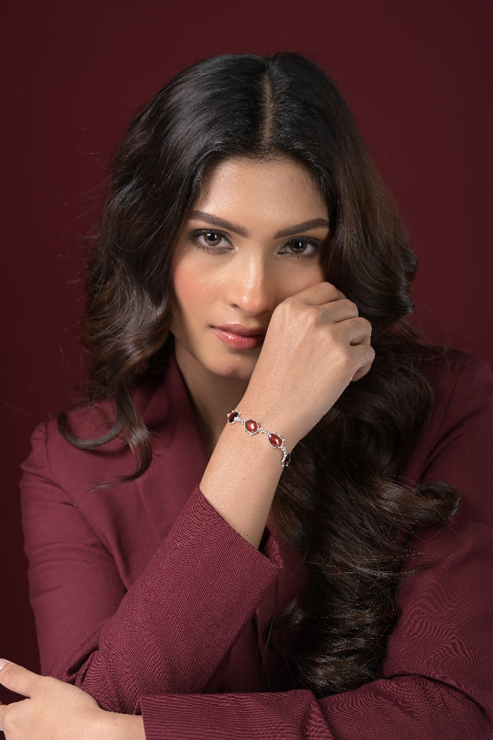 Woman wearing a burgundy outfit with a red Garnet bracelet and red background