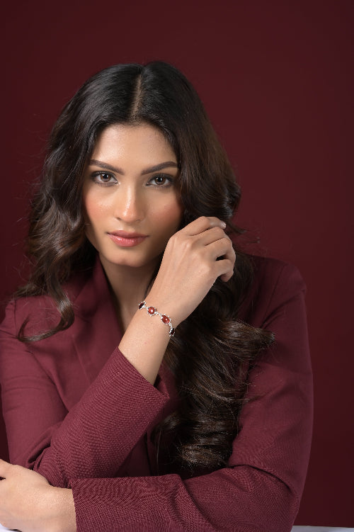 Woman wearing a burgundy outfit with a red Garnet bracelet and red background