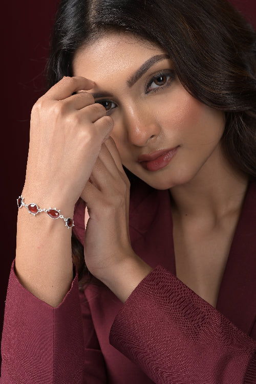 Woman wearing a bracelet with red Garnet gemstones on a dark background