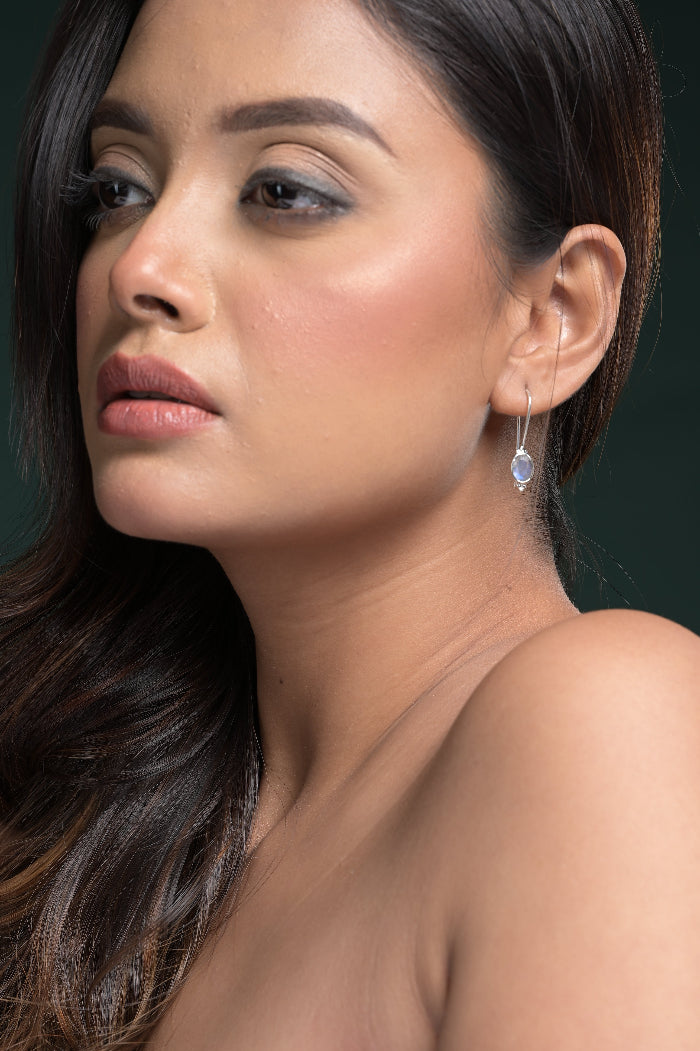 Close-up of a woman wearing a Labradorite Gemstone earring against a dark background