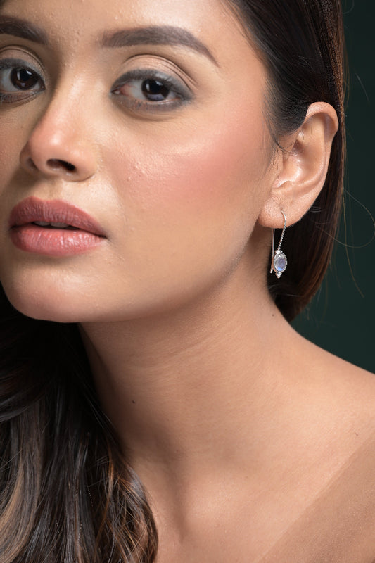 Close-up of a woman wearing a Labradorite Gemstone earring with a dark background