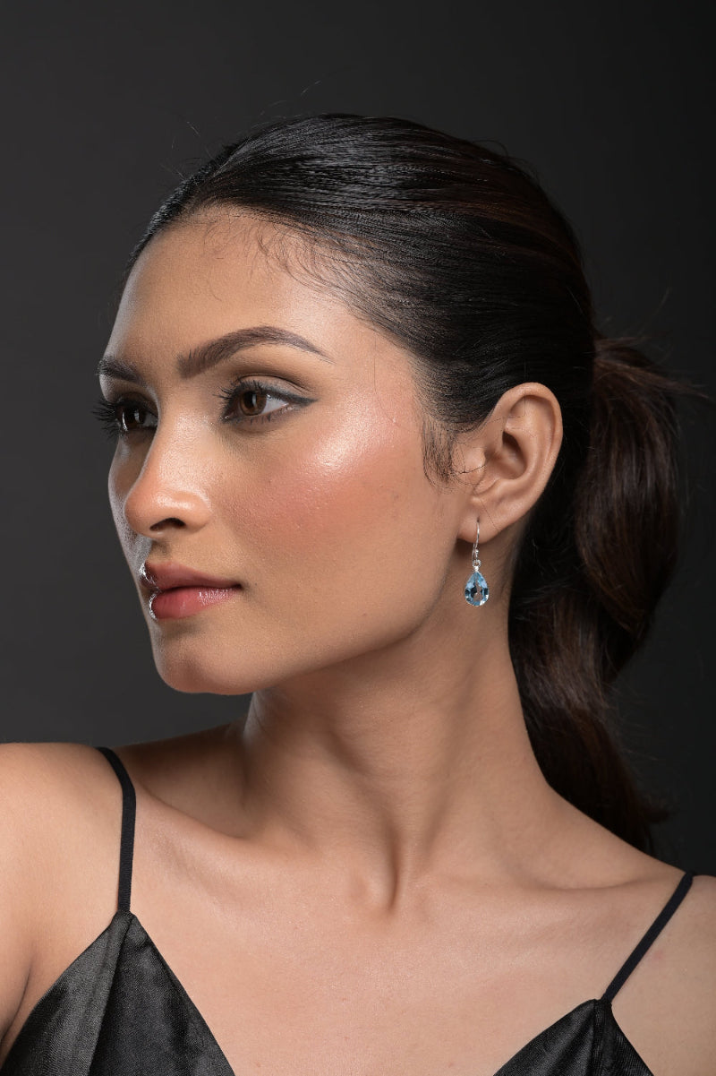 Woman wearing Blue Topaz Earrings a black top with a dark background