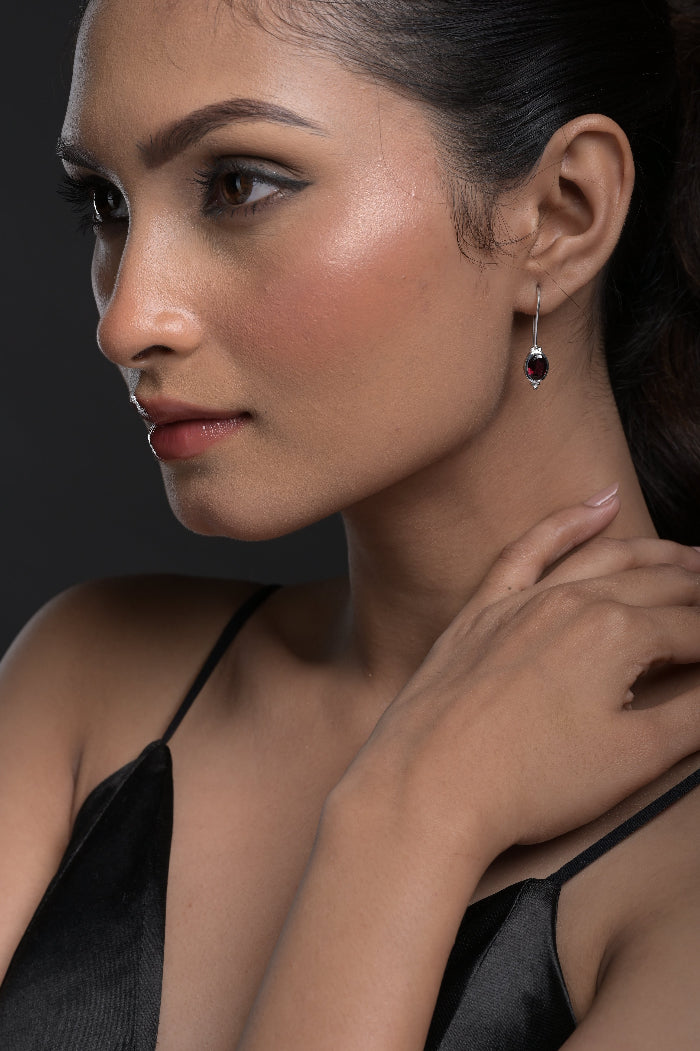 Close-up of a woman wearing a Red Garnet earring with a dark background