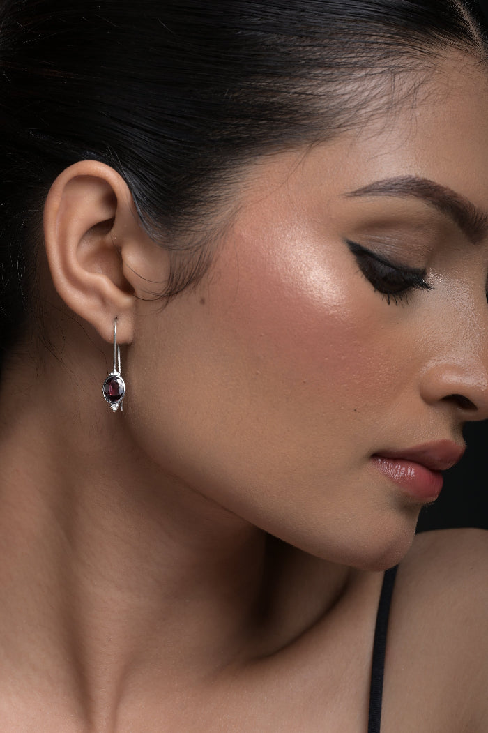 Close-up of a woman's ear with an Red Garnet earring, focusing on the jewelry.