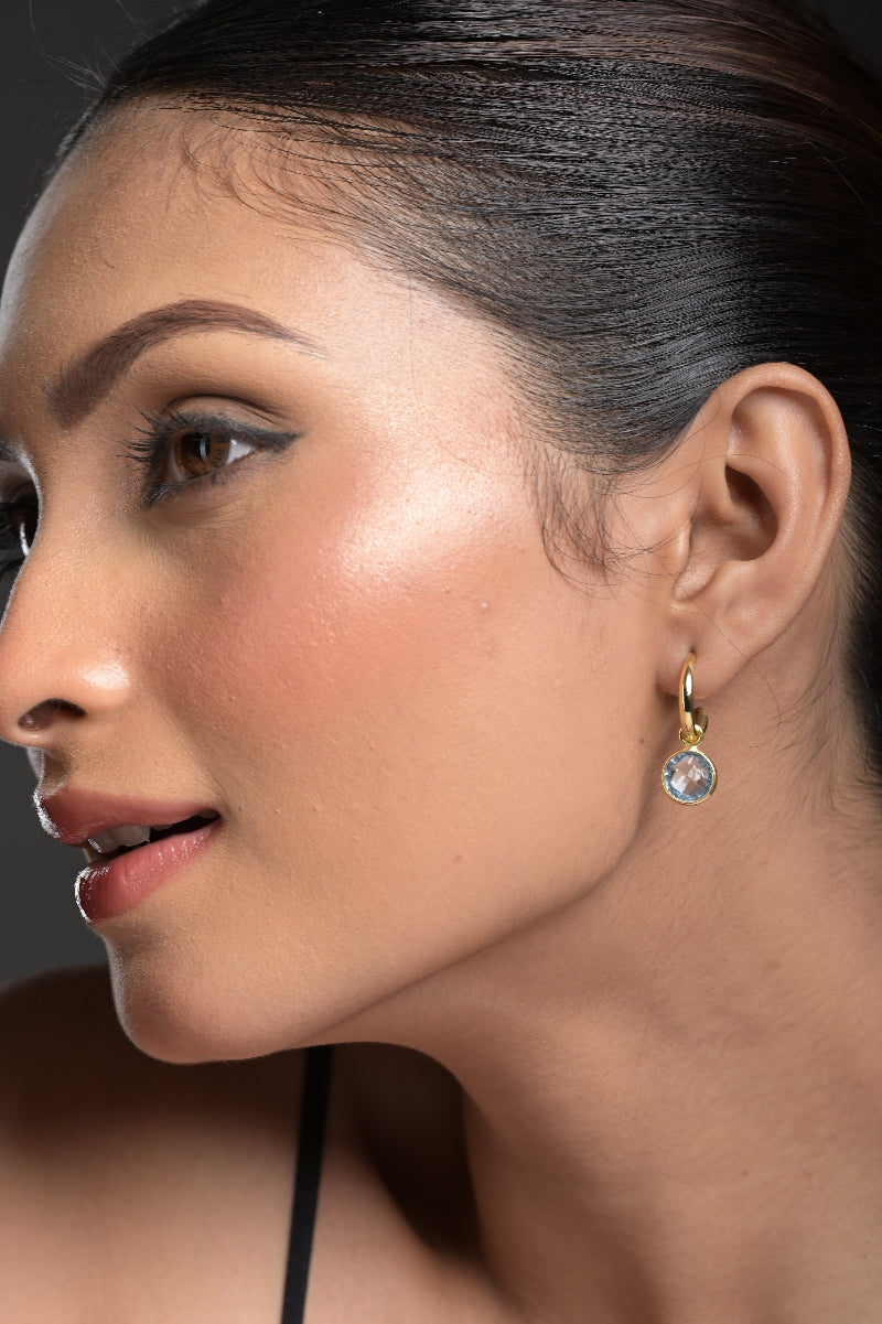 Close-up of a woman's ear with a Blue Topaz earring against a dark background
