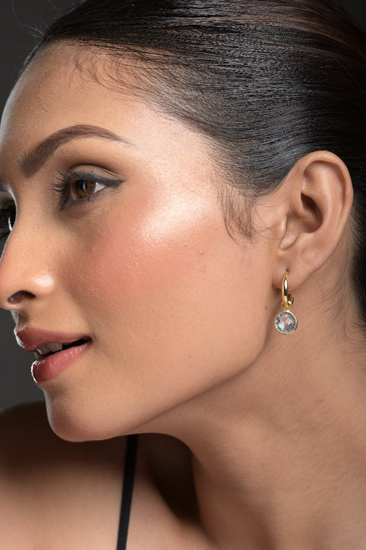 Close-up of a woman's ear with a Blue Topaz earring against a dark background