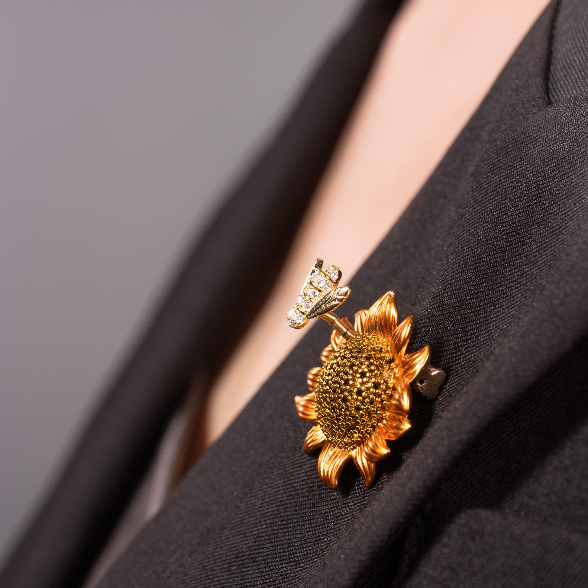 A brooch pin featuring a sunflower with a bee on top, made with cubic zirconia.