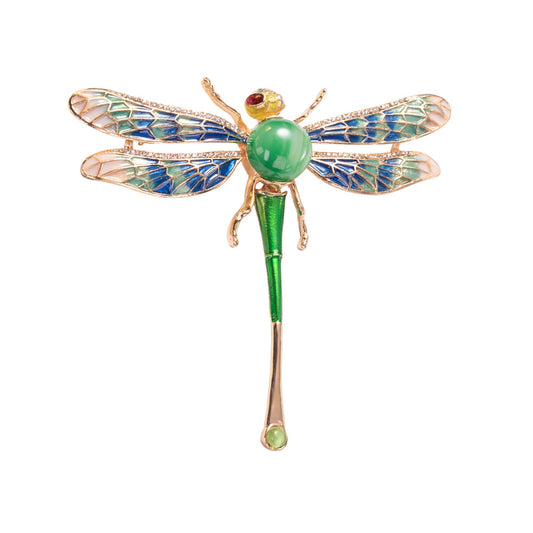 A colorful enameled dragonfly brooch with a green body and blue wings, accented with a red stone.