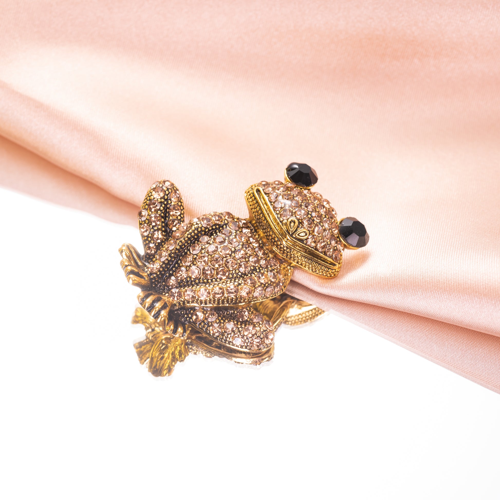 A yellow gold over brass brooch pin featuring a sparkling, champagne crystal-encrusted frog design.