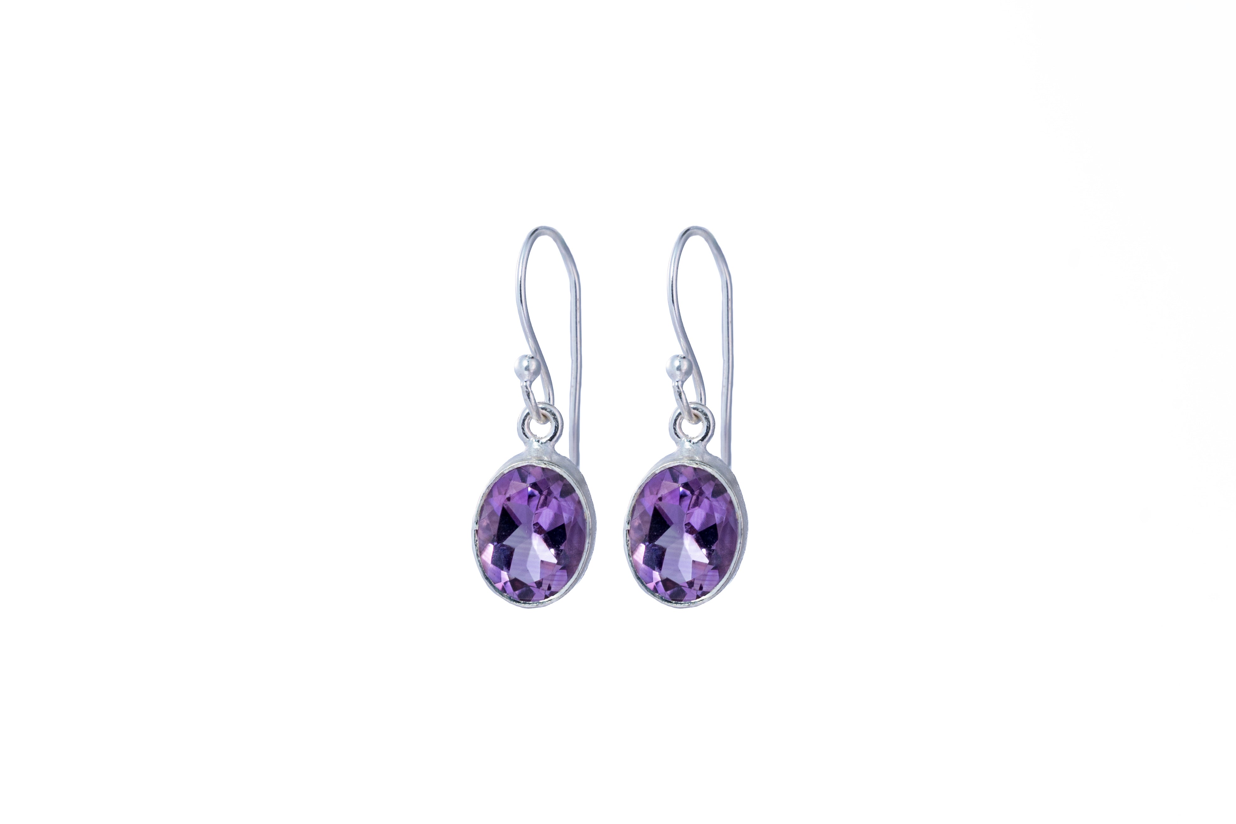Pair of silver earrings with purple gemstones on a white background