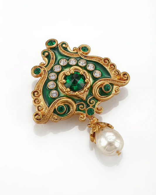 Decorative brooch with green gemstones, gold accents, and a pearl on a white background