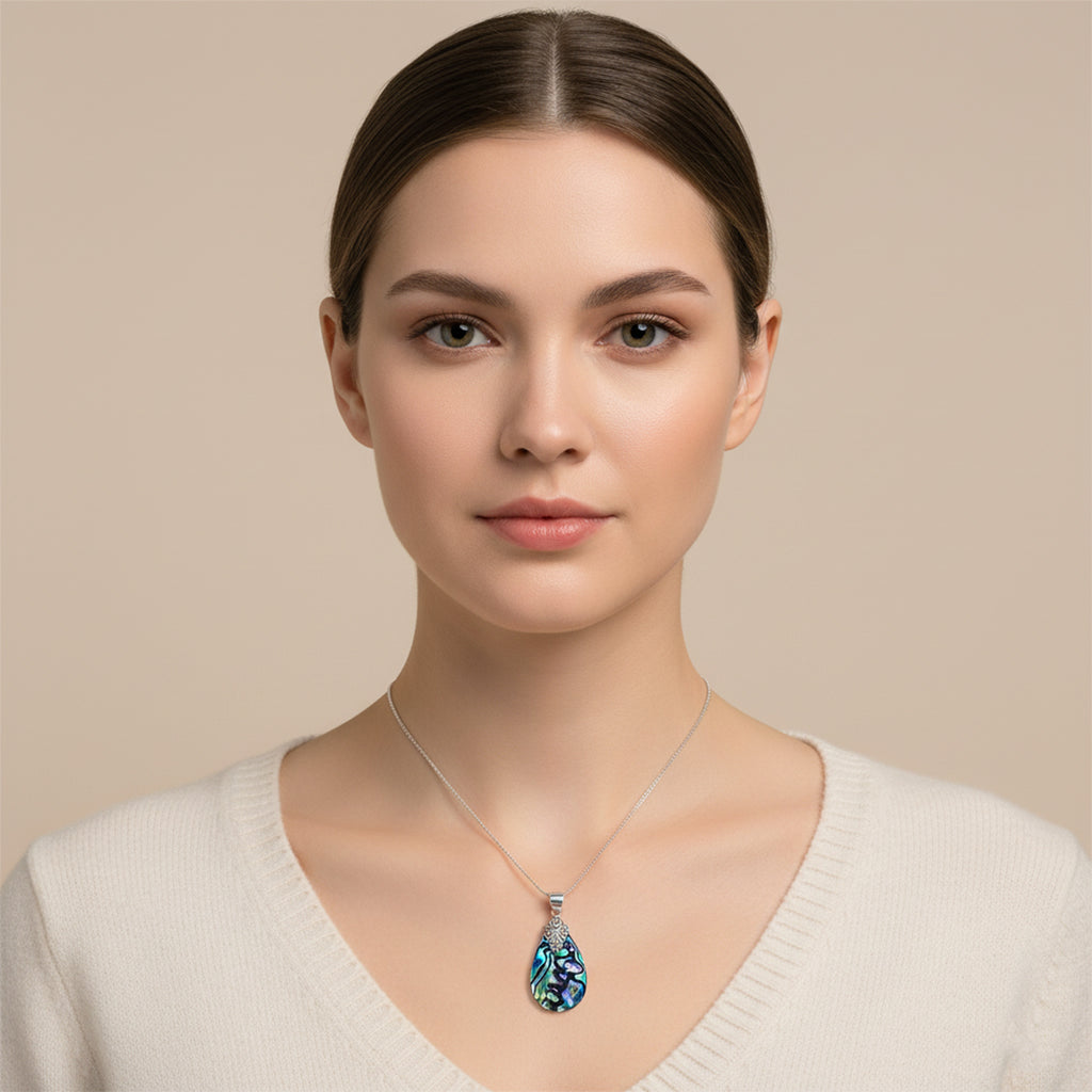 Woman wearing a necklace with a blue pendant against a beige background