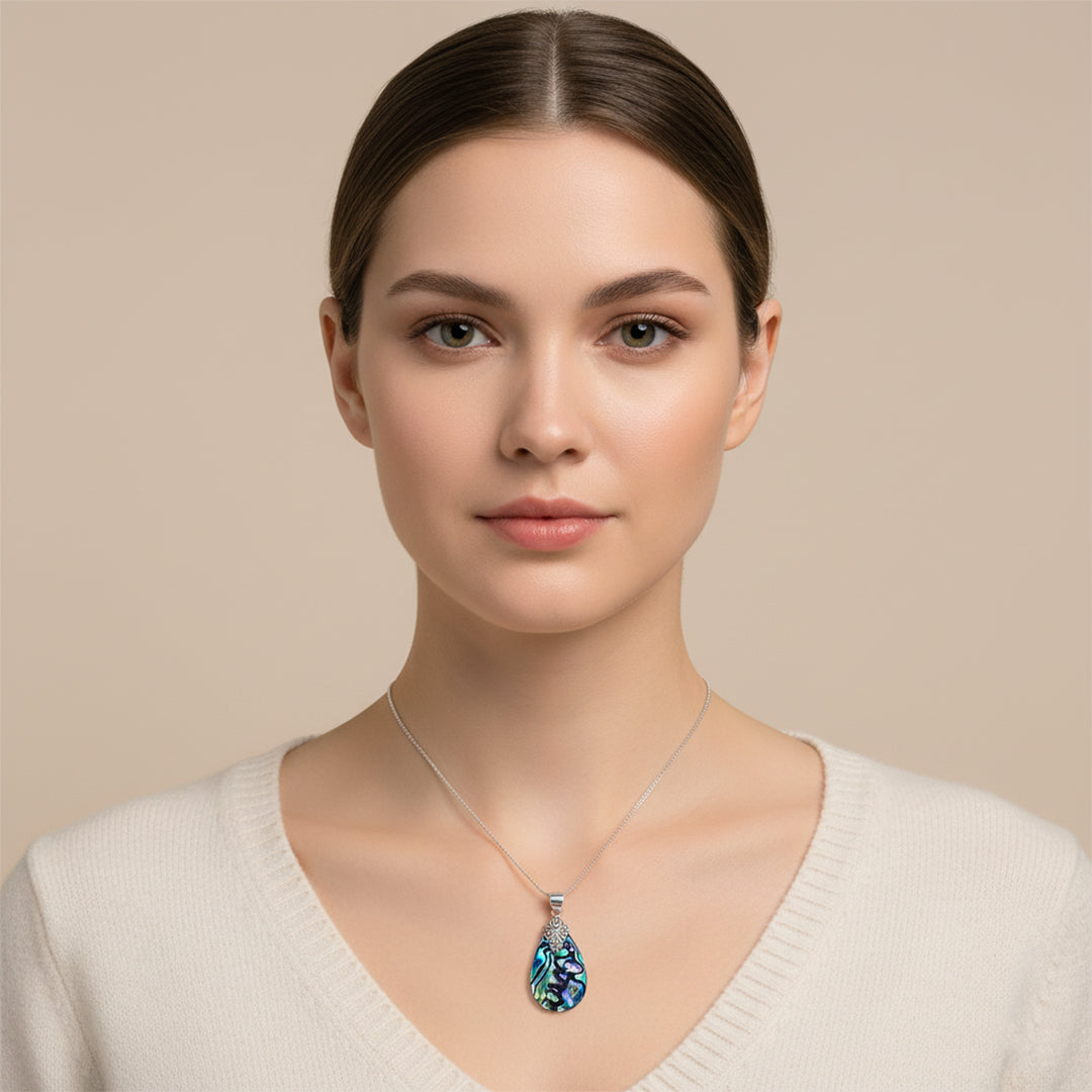 Woman wearing a necklace with a blue pendant against a beige background