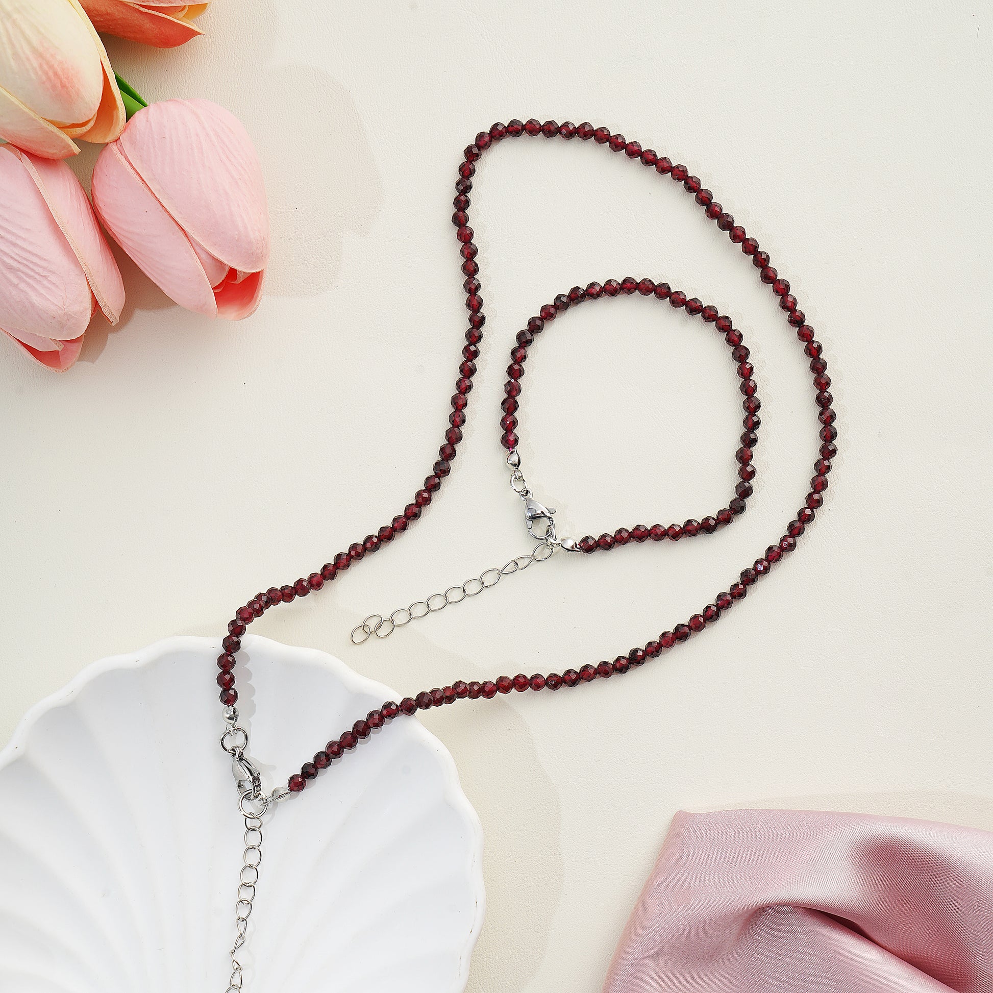 Beaded necklace on a white plate with pink tulips in the background