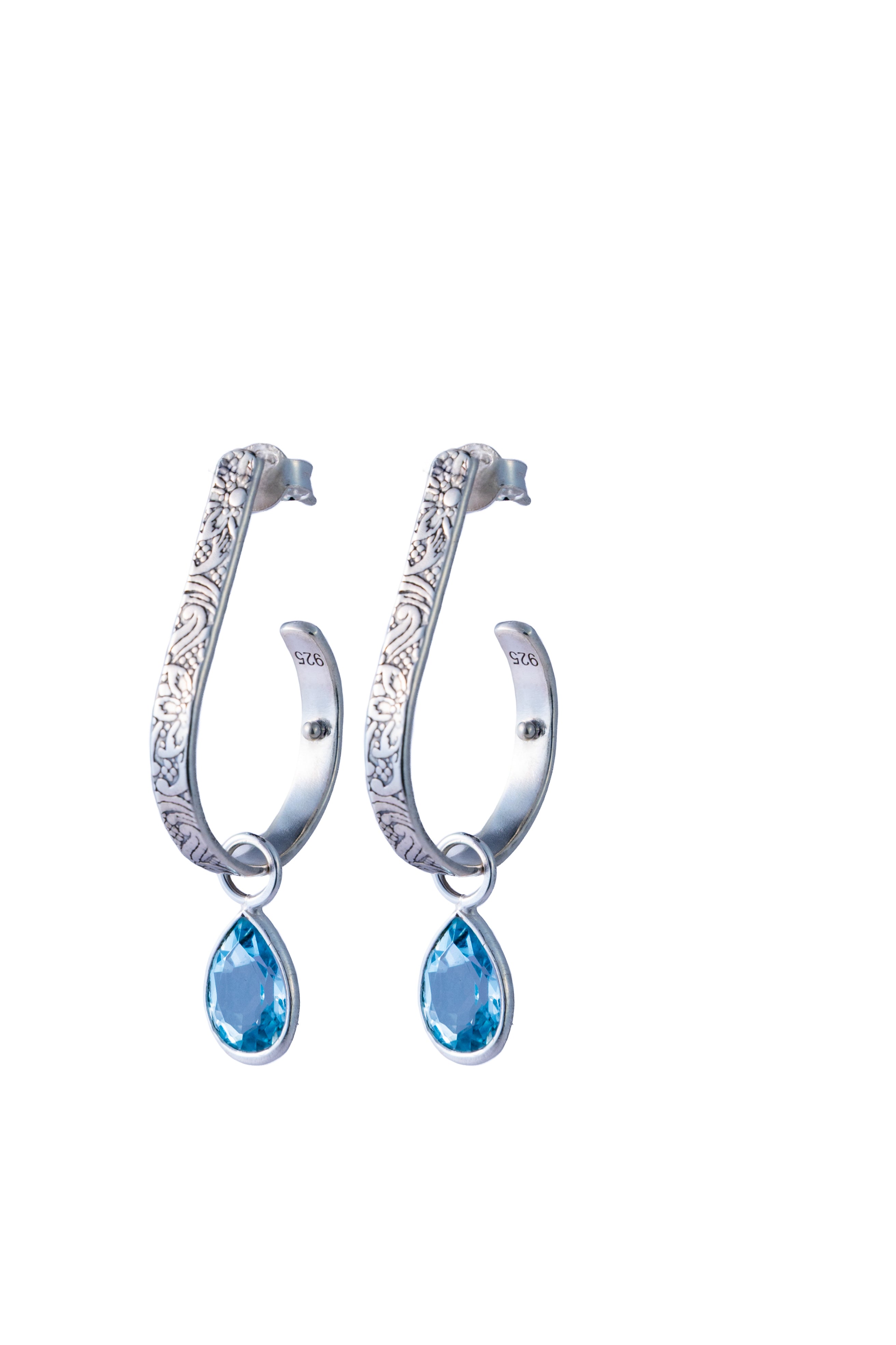Pair of silver hoop earrings with blue Topaz teardrop stones on a white background