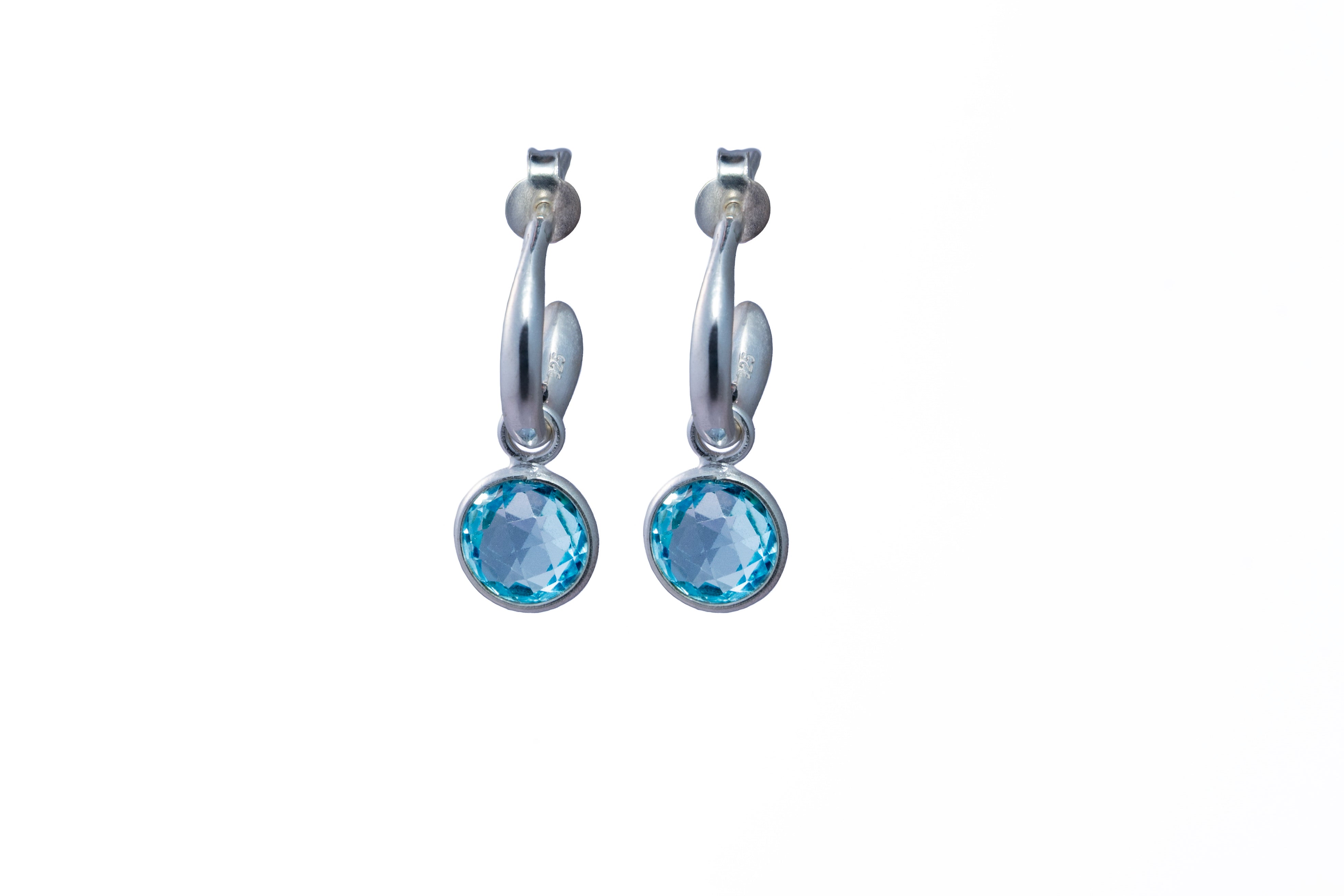 Silver hoop earrings with blue Topaz gemstones on a white background