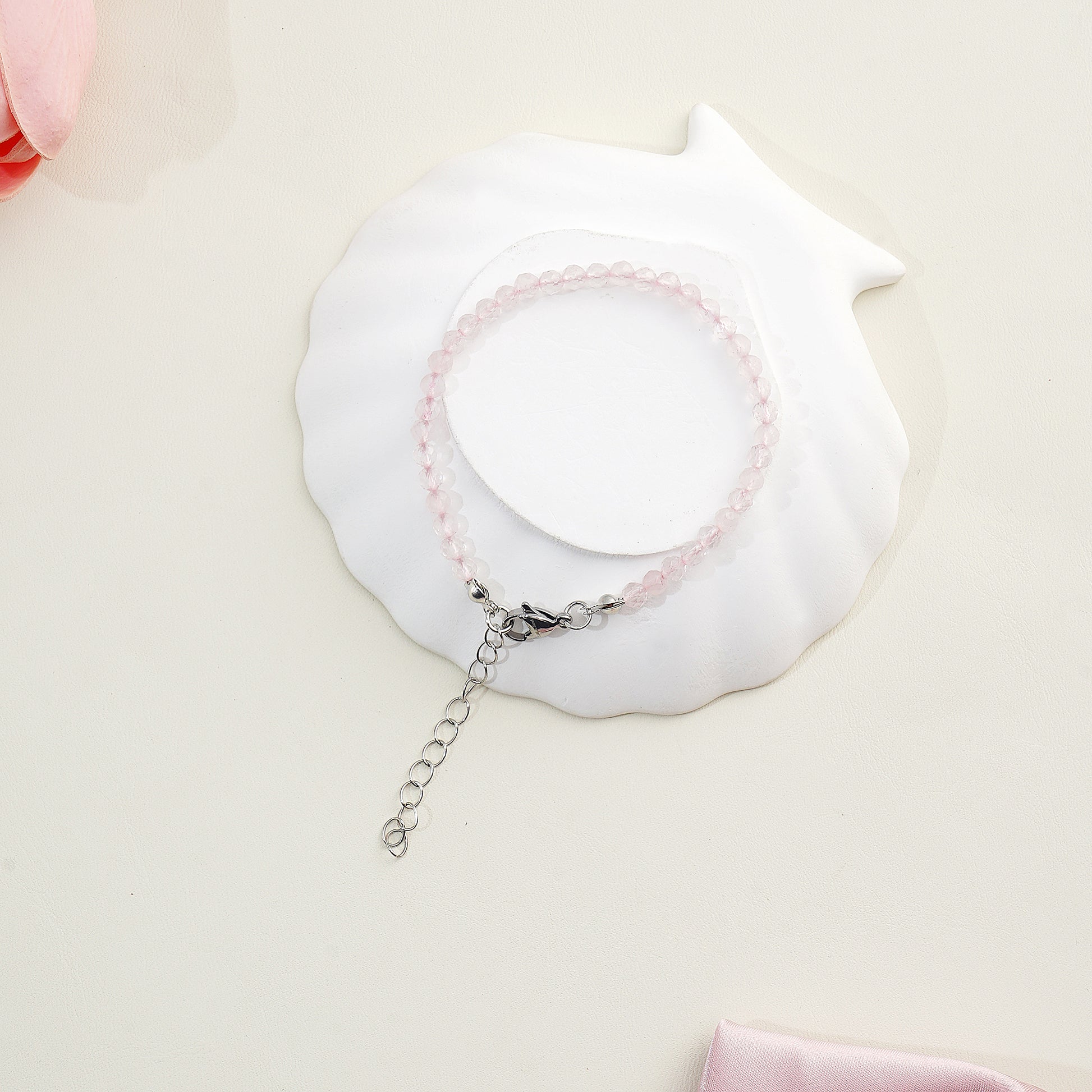 Bracelet with pink beads on a white shell against a light pink background