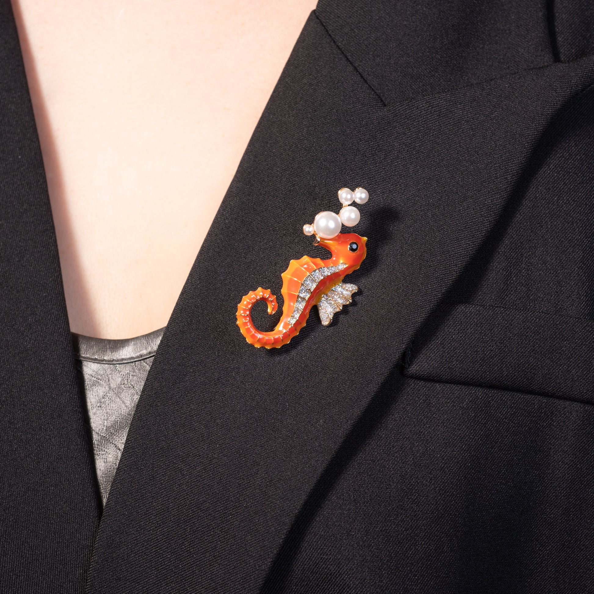 Close-up of a vibrant seahorse pin worn on the lapel of a beige linen blazer