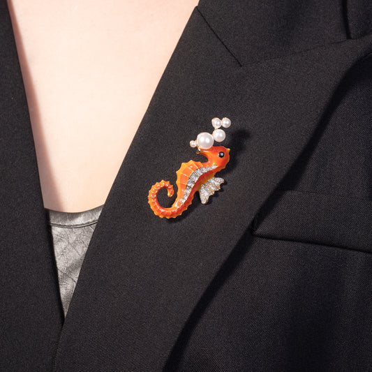 Close-up of a vibrant seahorse pin worn on the lapel of a beige linen blazer