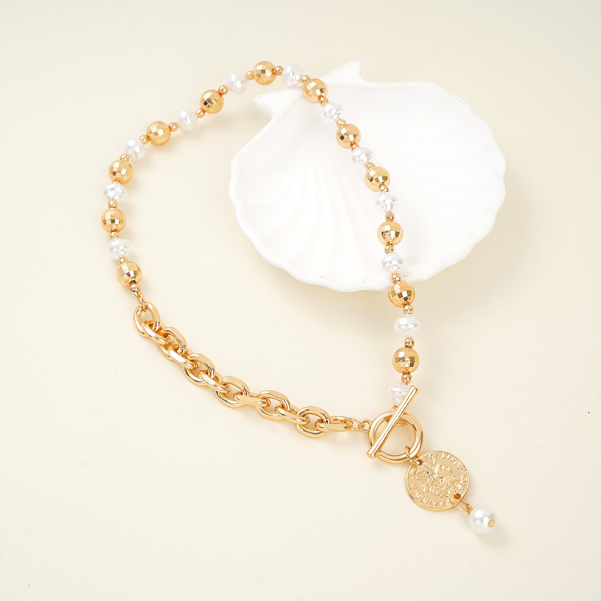 the Roman coin motif, lustrous pearl accent, and yellow gold T-bar closure