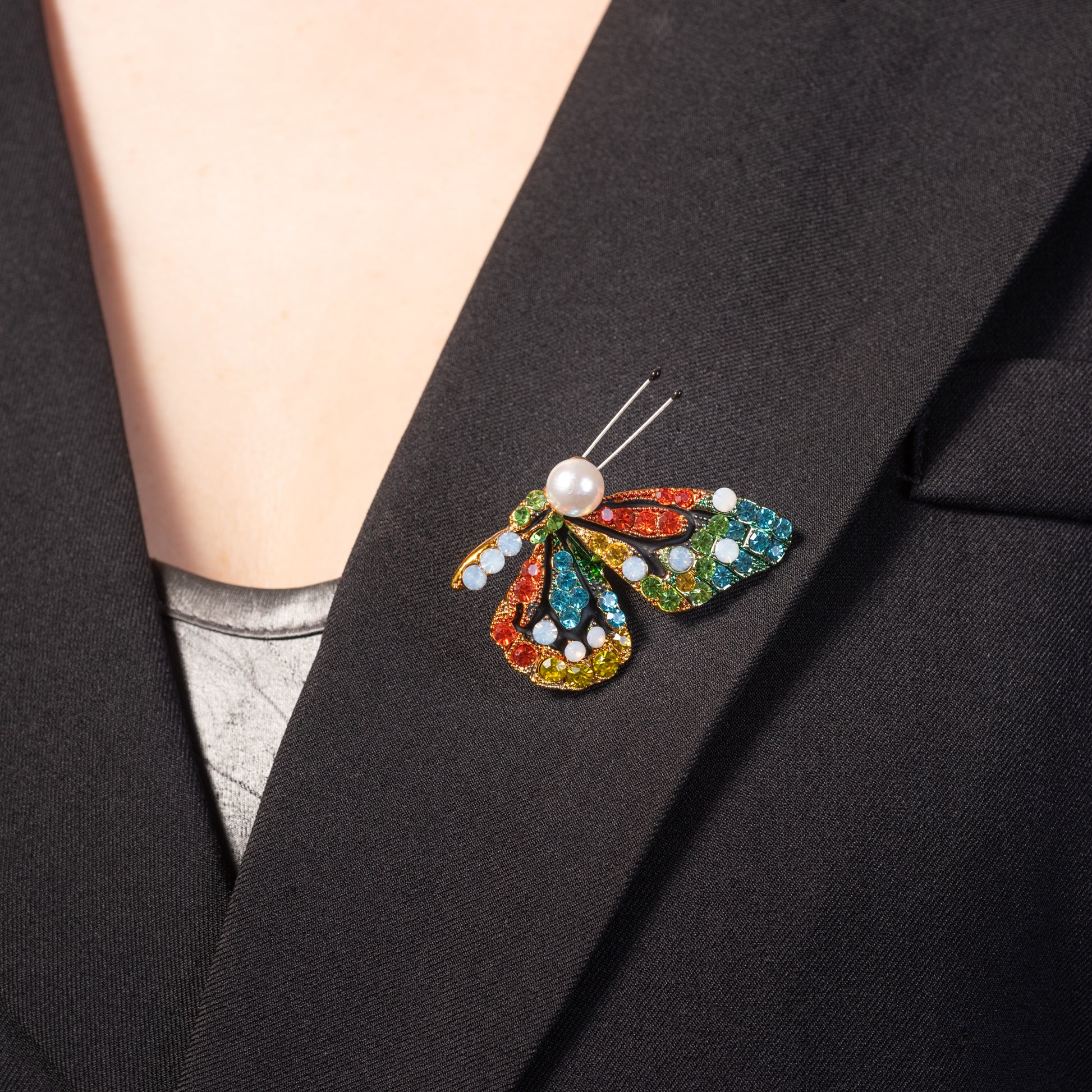 Colorful butterfly brooch with pearl center on a black blazer