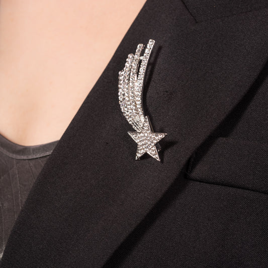 A silver-colored brooch in the shape of a shooting star adorned with sparkling crystals.