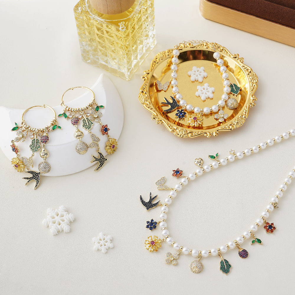 Jewelry set including earrings and a necklace with floral and bird charms on a white surface-Stars and Vogue