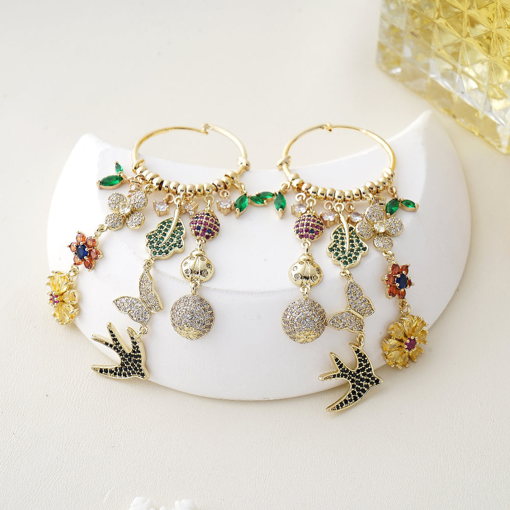 Gold hoop earrings with colorful charms on a white surface-Stars and Vogue