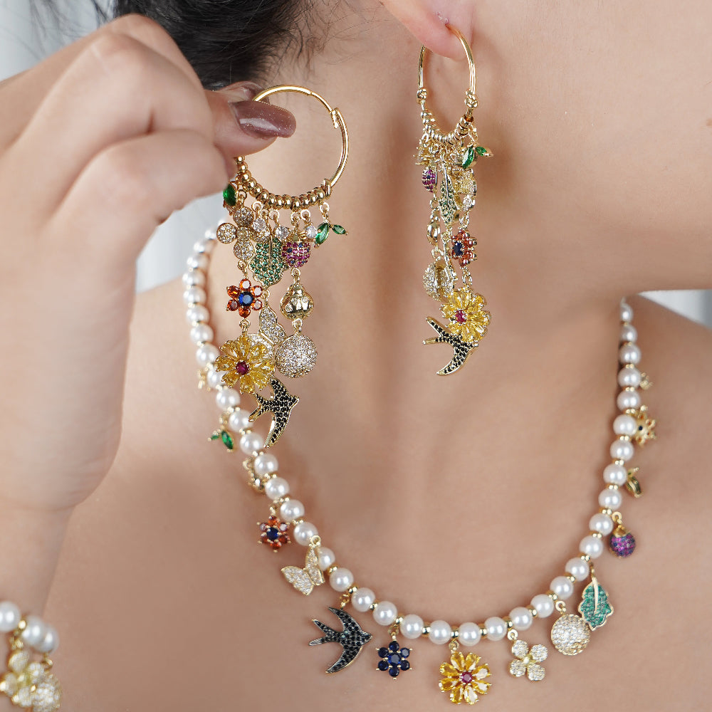 Close-up of a person wearing a pearl necklace and colorful earrings with floral and leaf charms.-Stars and Vogue