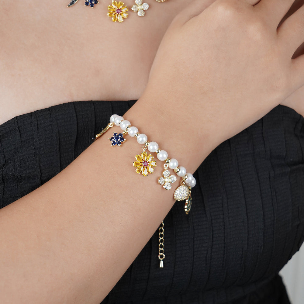 Pearl bracelet with floral and butterfly charms on a wrist against a neutral background-Stars and Vogue