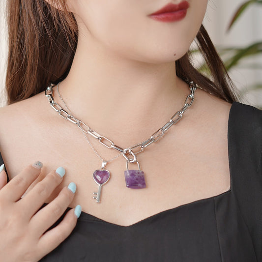 Necklace with key and lock pendants on a person wearing a black top.