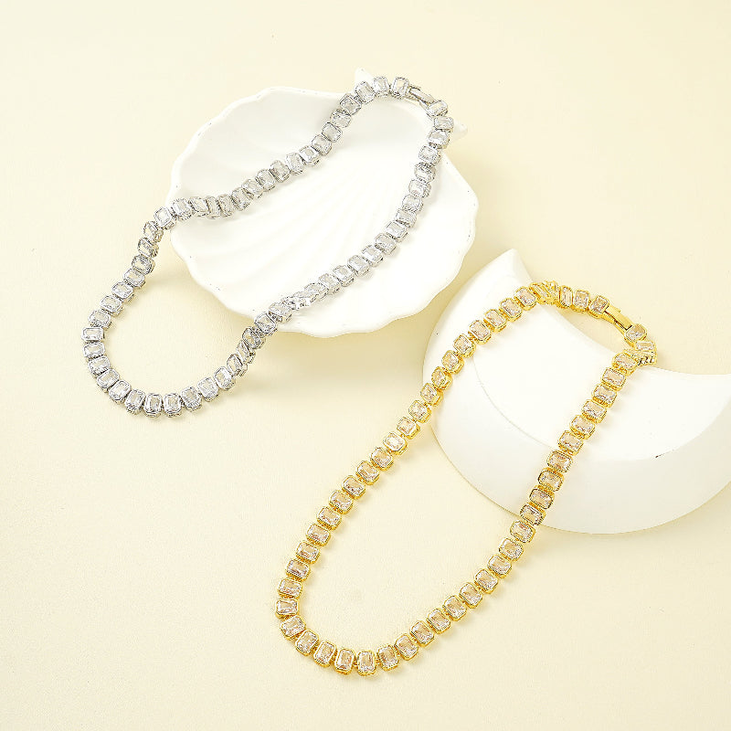 Gold and silver Tennis Choker Necklace on white stones with a beige background