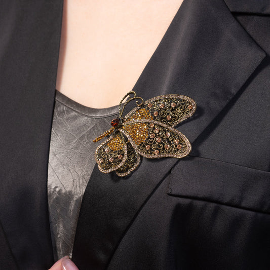 Butterfly-shaped brooch with gemstones on a black blazer