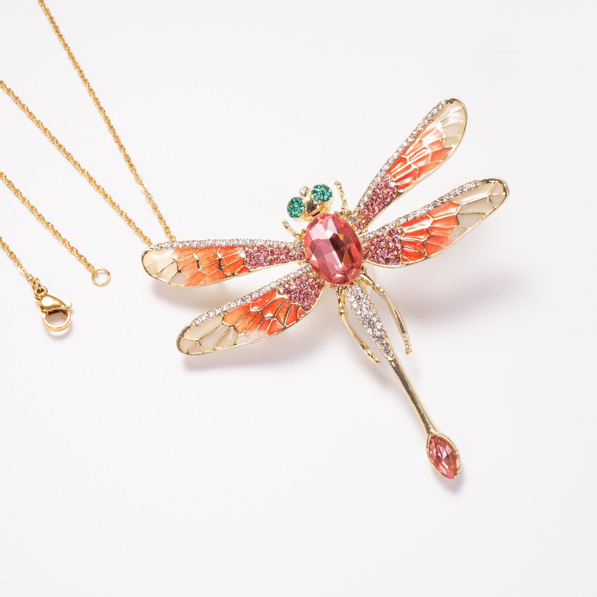 Dragonfly-shaped pendant with gemstones on a white background