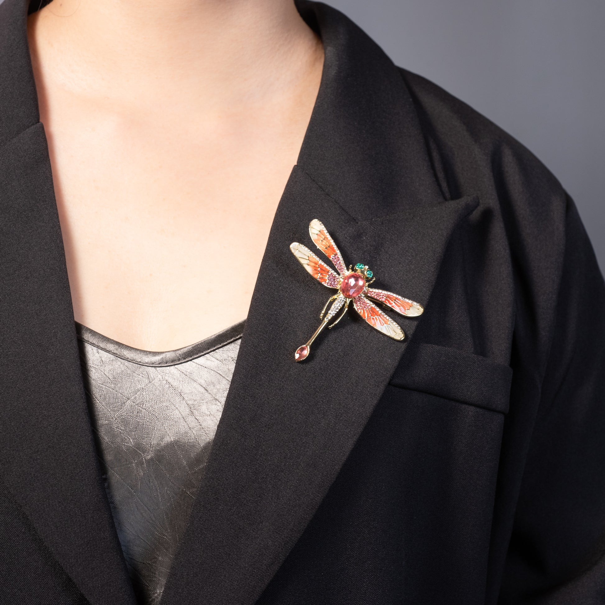 Dragonfly brooch on a black blazer against a gray background