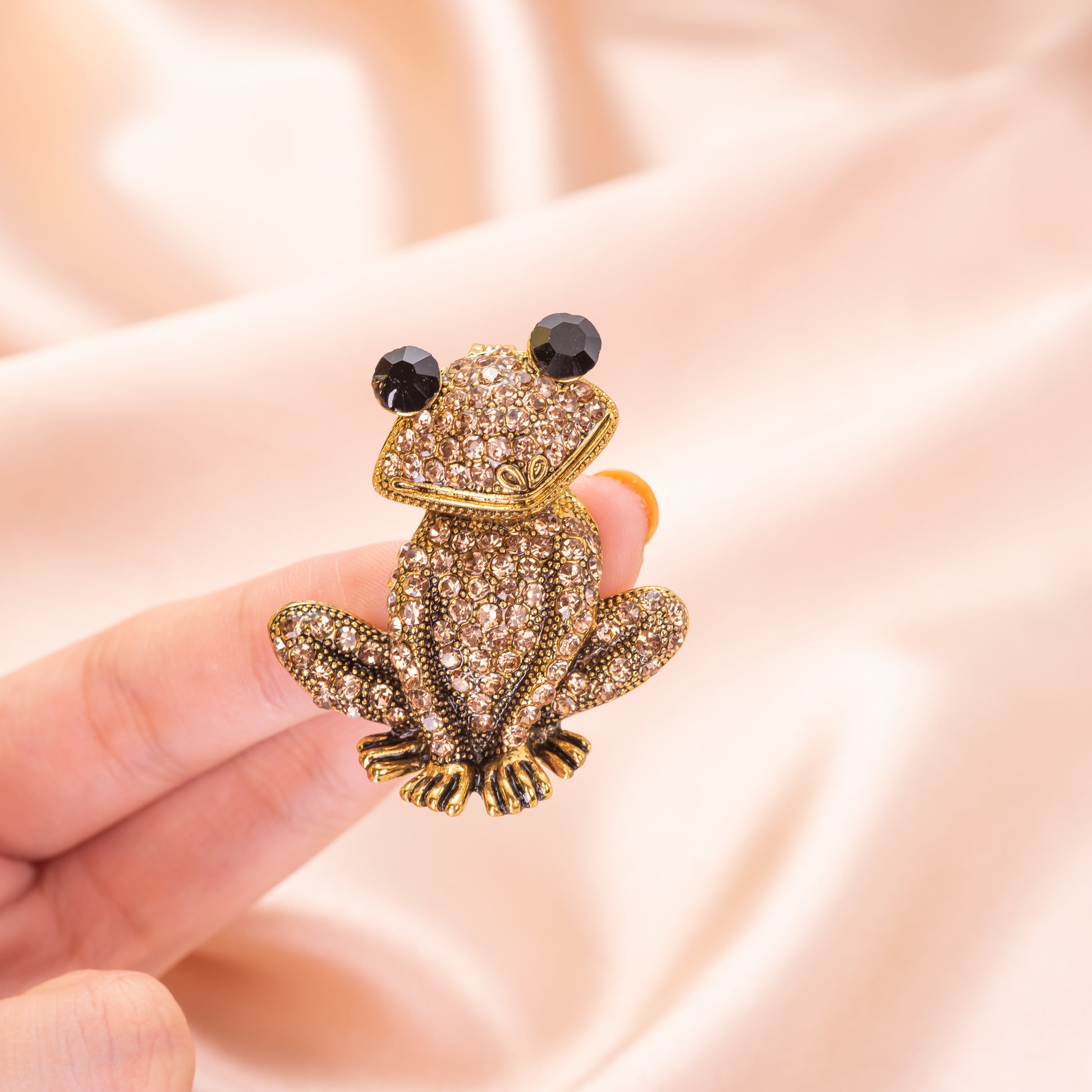 A yellow gold over brass brooch pin featuring a sparkling, champagne crystal-encrusted frog design.