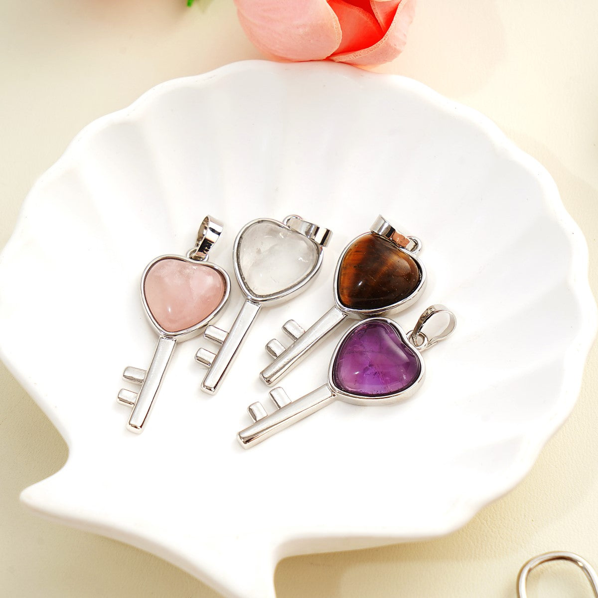Four heart-shaped stone pendants on silver keychains displayed on a white dish.