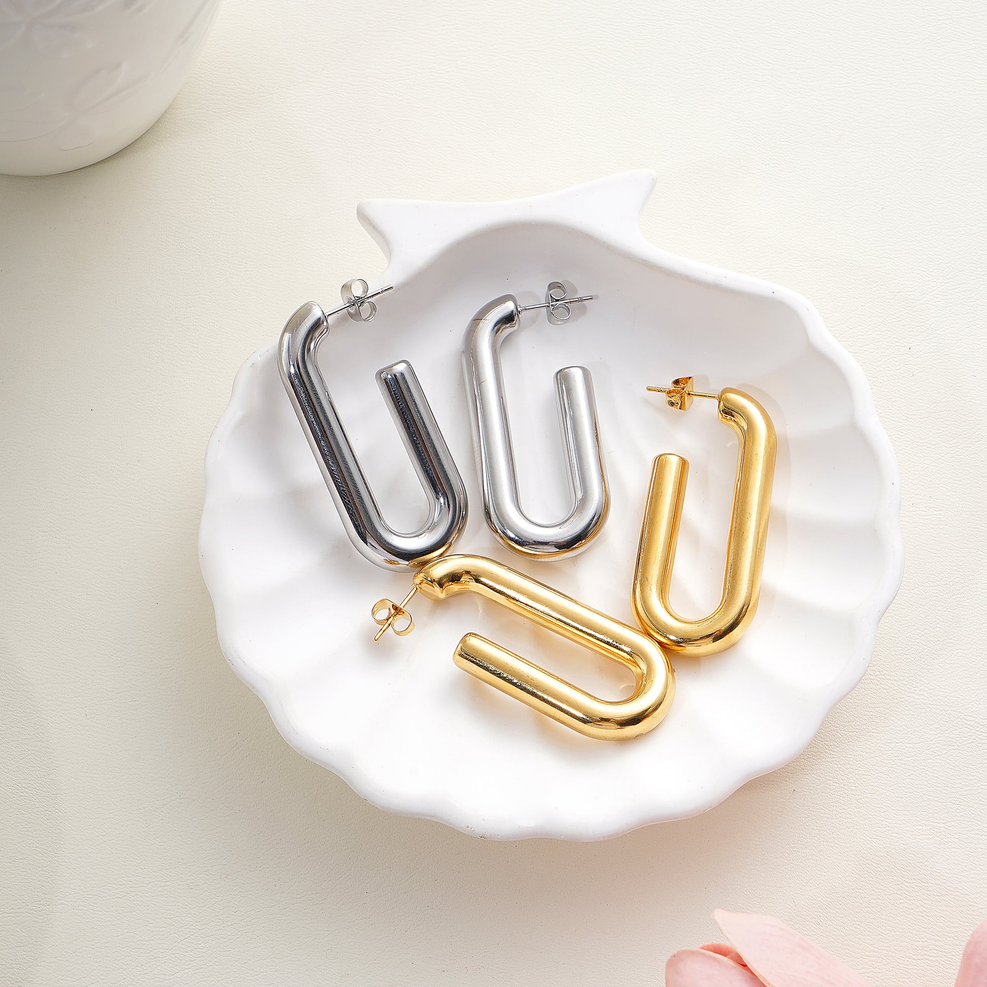 Gold and silver U-shaped hoop earrings on a white dish.