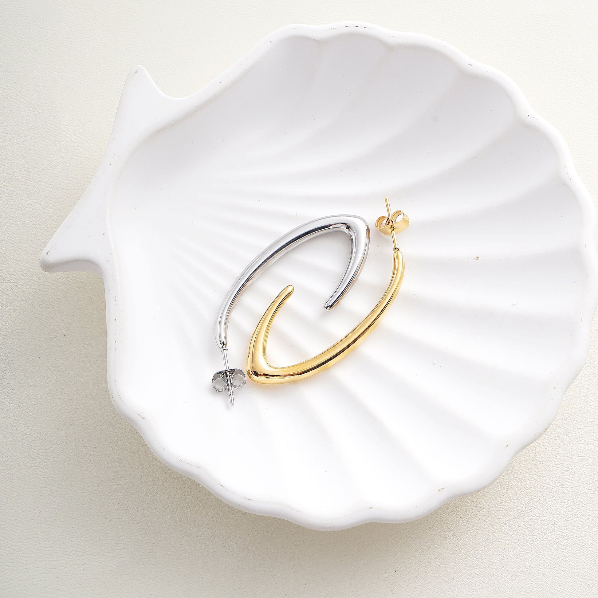 Gold and silver hoop earrings on a white shell