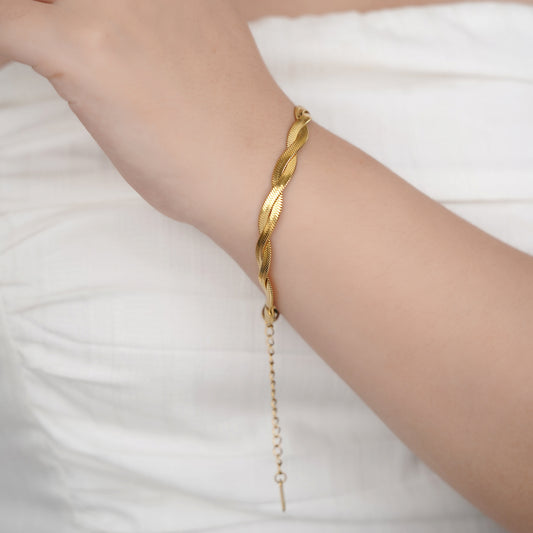 Gold bracelet on a person's wrist against a white background