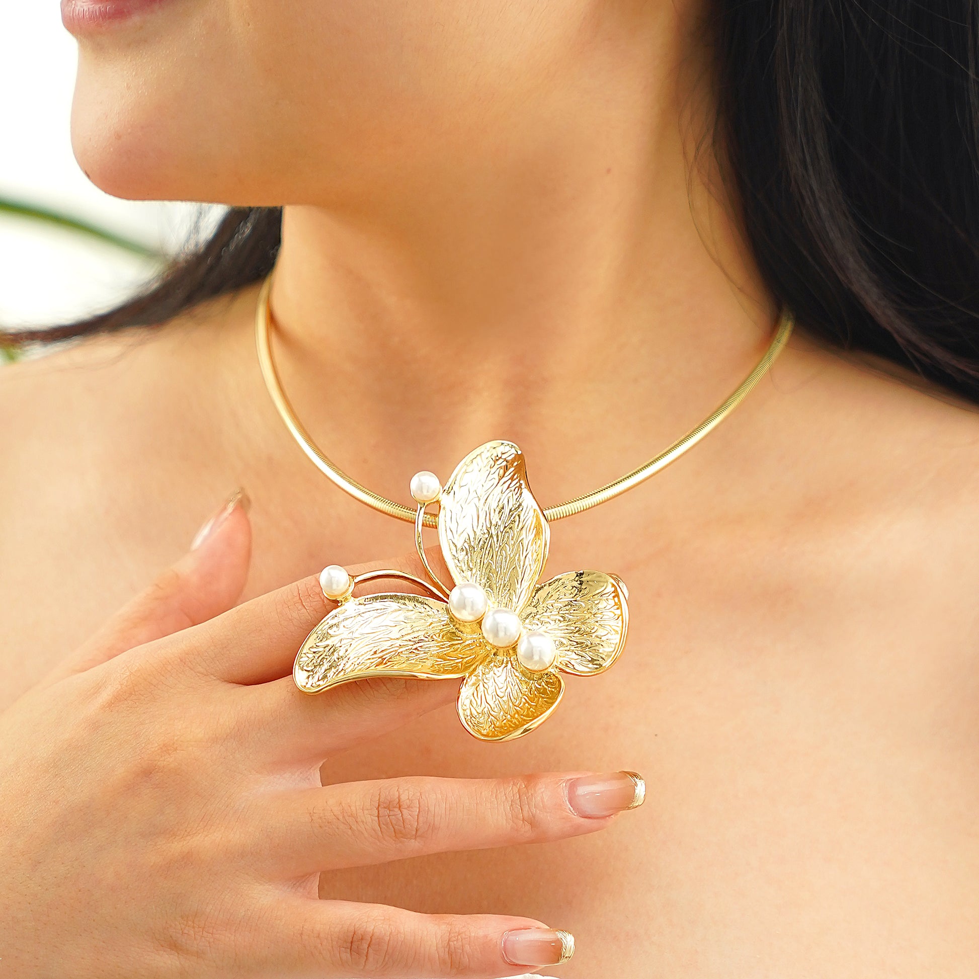 Gold butterfly necklace with pearls worn by a person