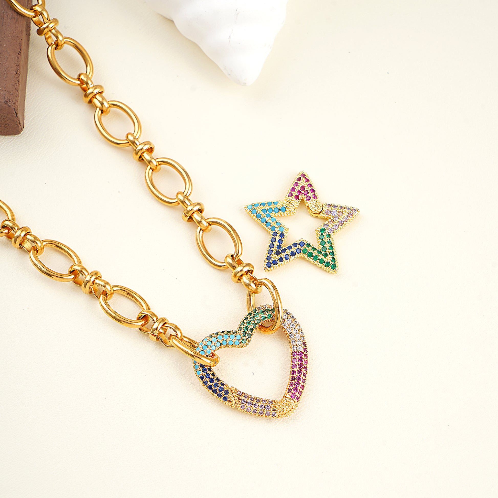 Gold chain necklace with colorful star and heart pendants on a white background