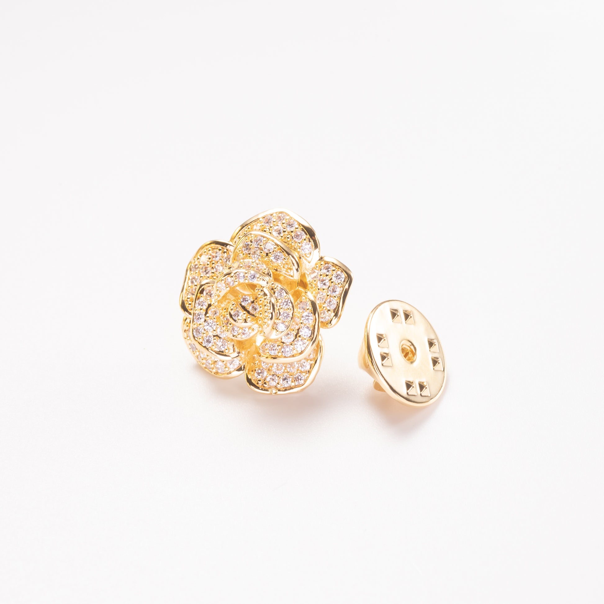 Gold floral earring with clear gemstones on a white background