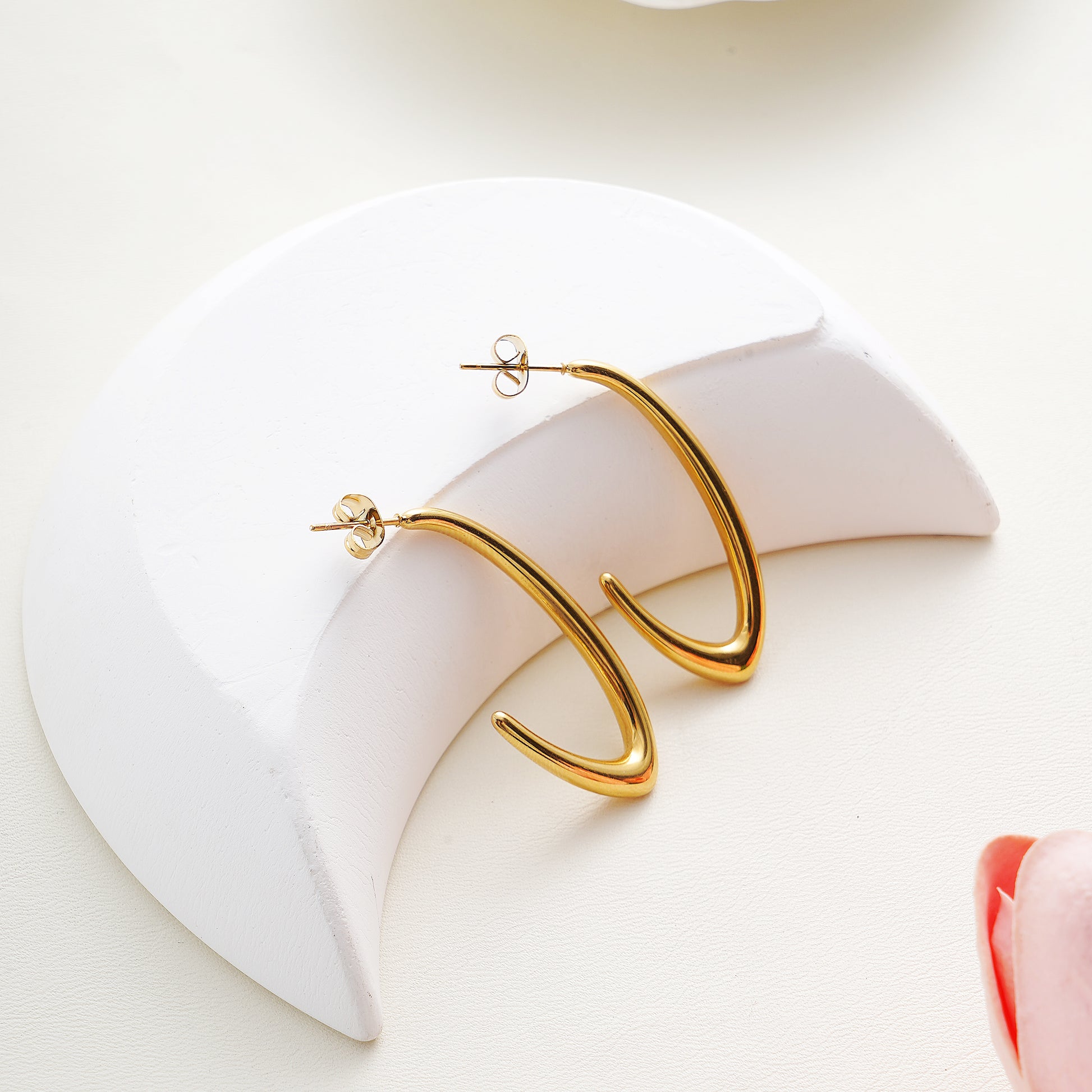 Gold hoop earrings on a white heart-shaped object