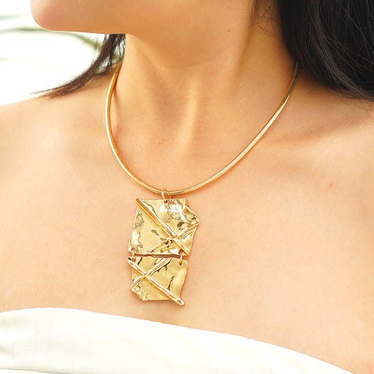 Gold necklace with a geometric pendant worn by a person