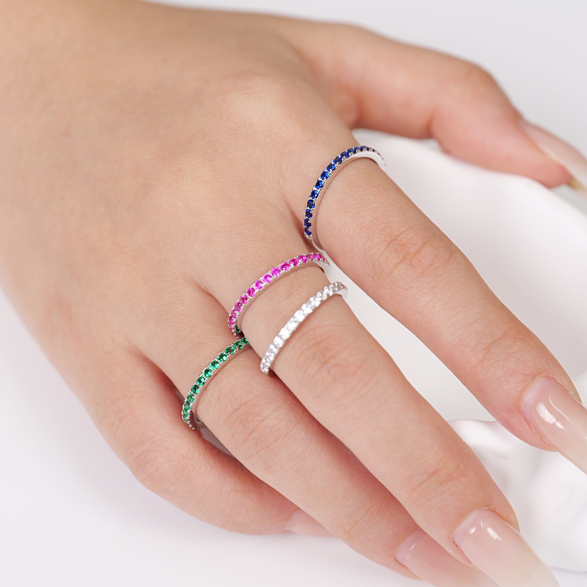 Hand wearing multiple colorful rings 